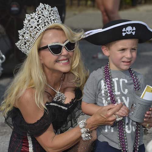 Woman dressed as a queen posing with a young boy in a pirate hat